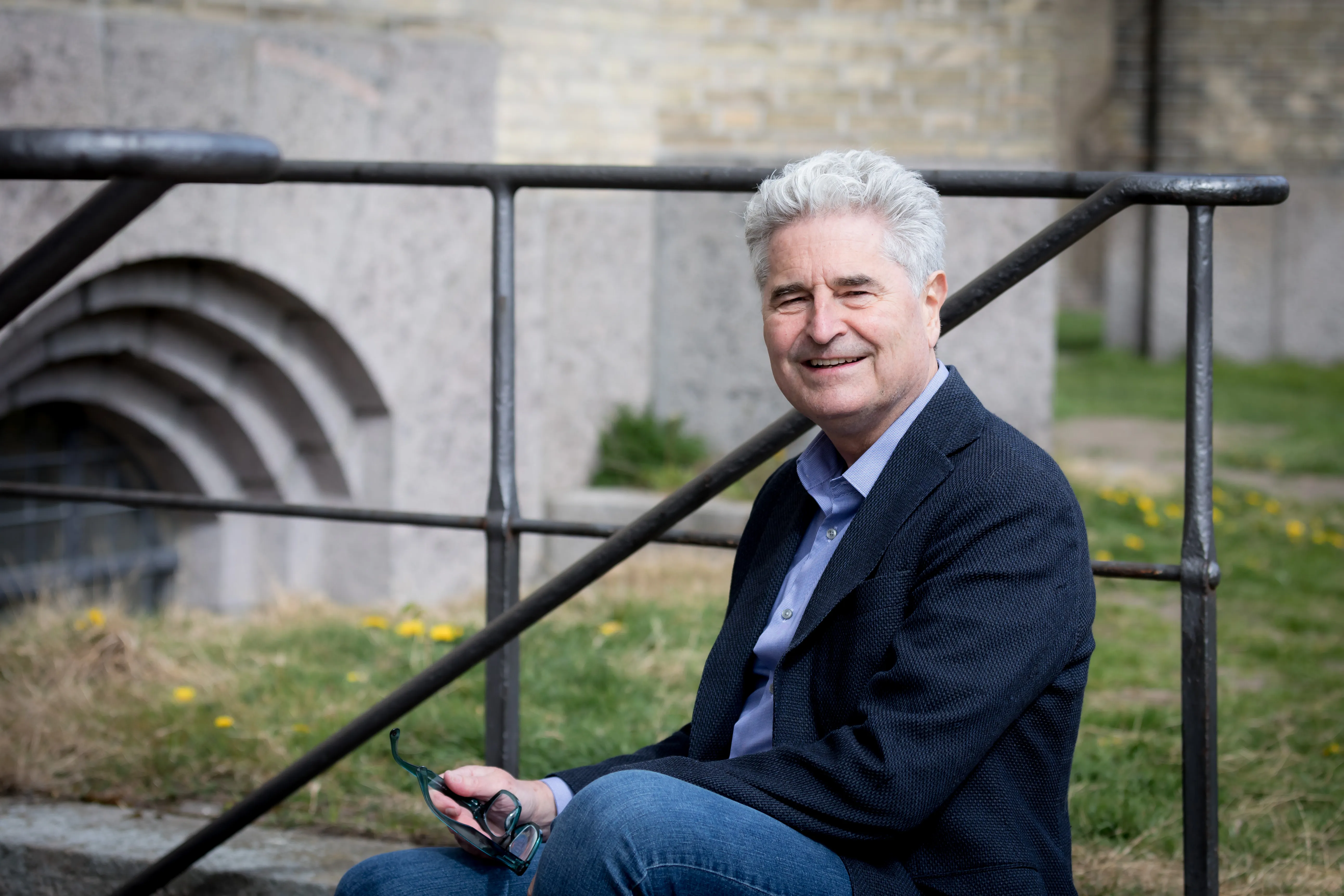 Thomas Lisbjerg-Jensen siddende på trappen ved en gammel stenbygning