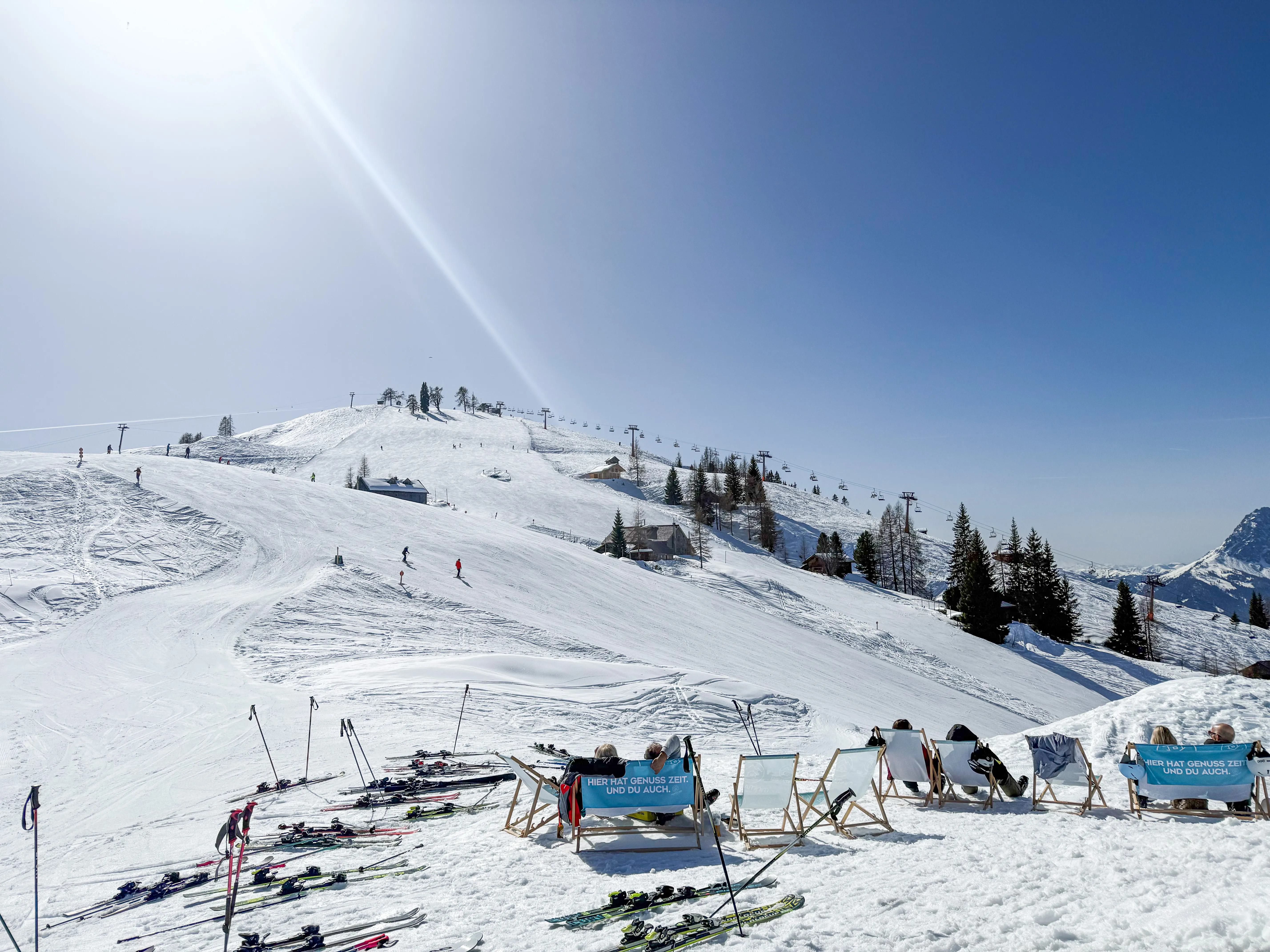 Solrig pisteudsigt med skiliggestole og bjergstation i baggrunden